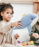 Un bambino che gioca con un peluche a forma di delfino